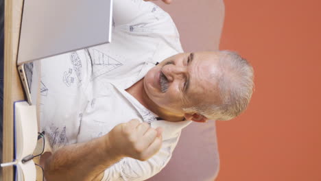 Vertical-video-of-Old-man-looks-at-laptop-and-rejoices.